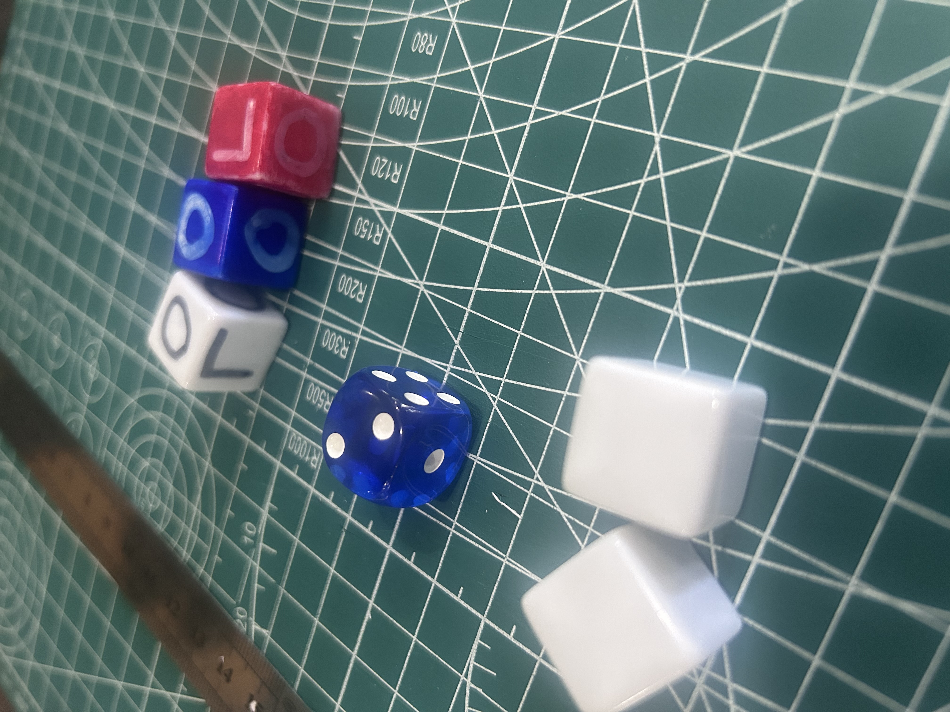 Five dice on a cutting mat — the OPEN/LOCKED custom dice, a standard d6, and blank Ivory Die tokens