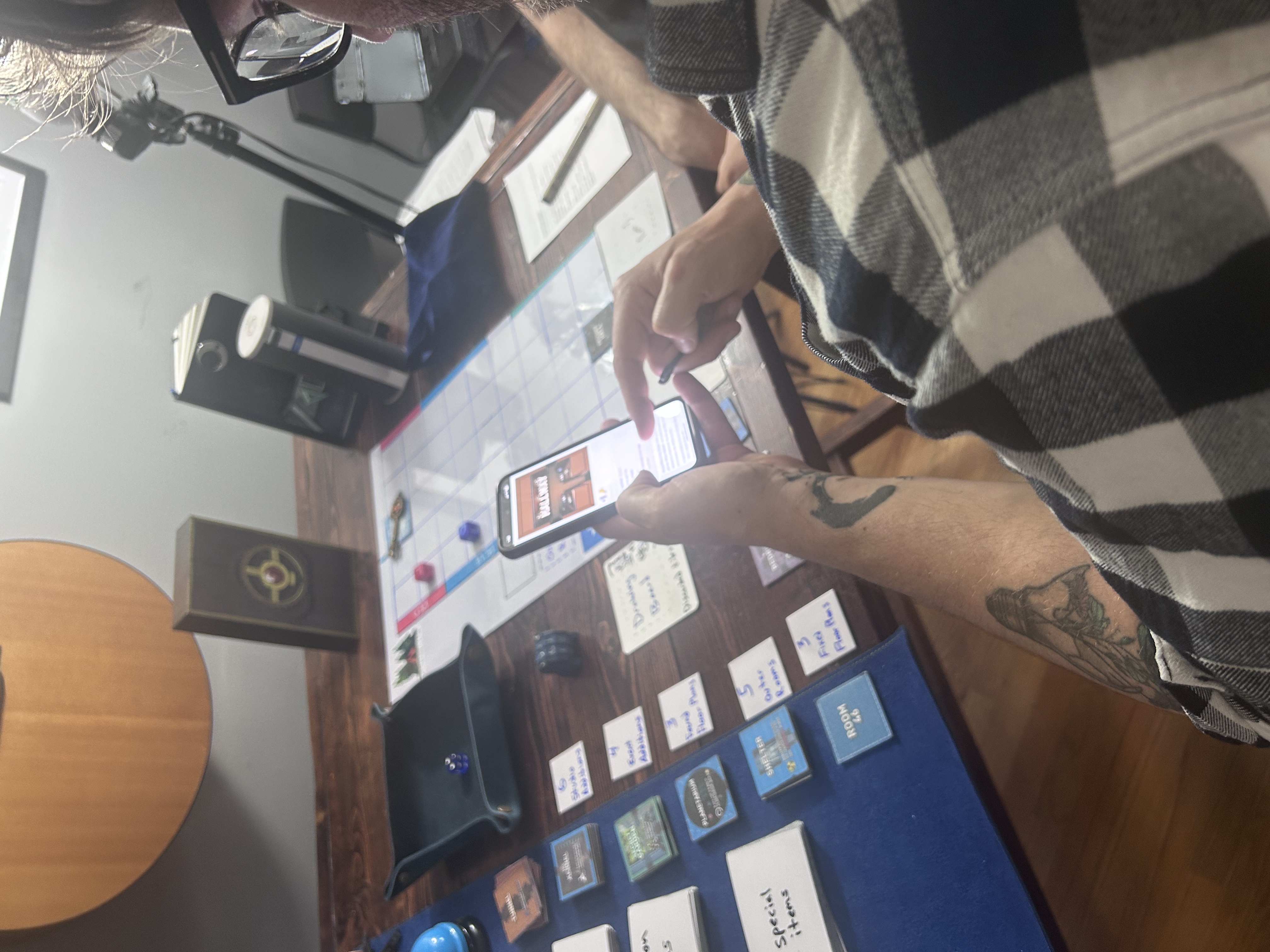Wide shot of Mike with phone showing QR landing page, board visible in background