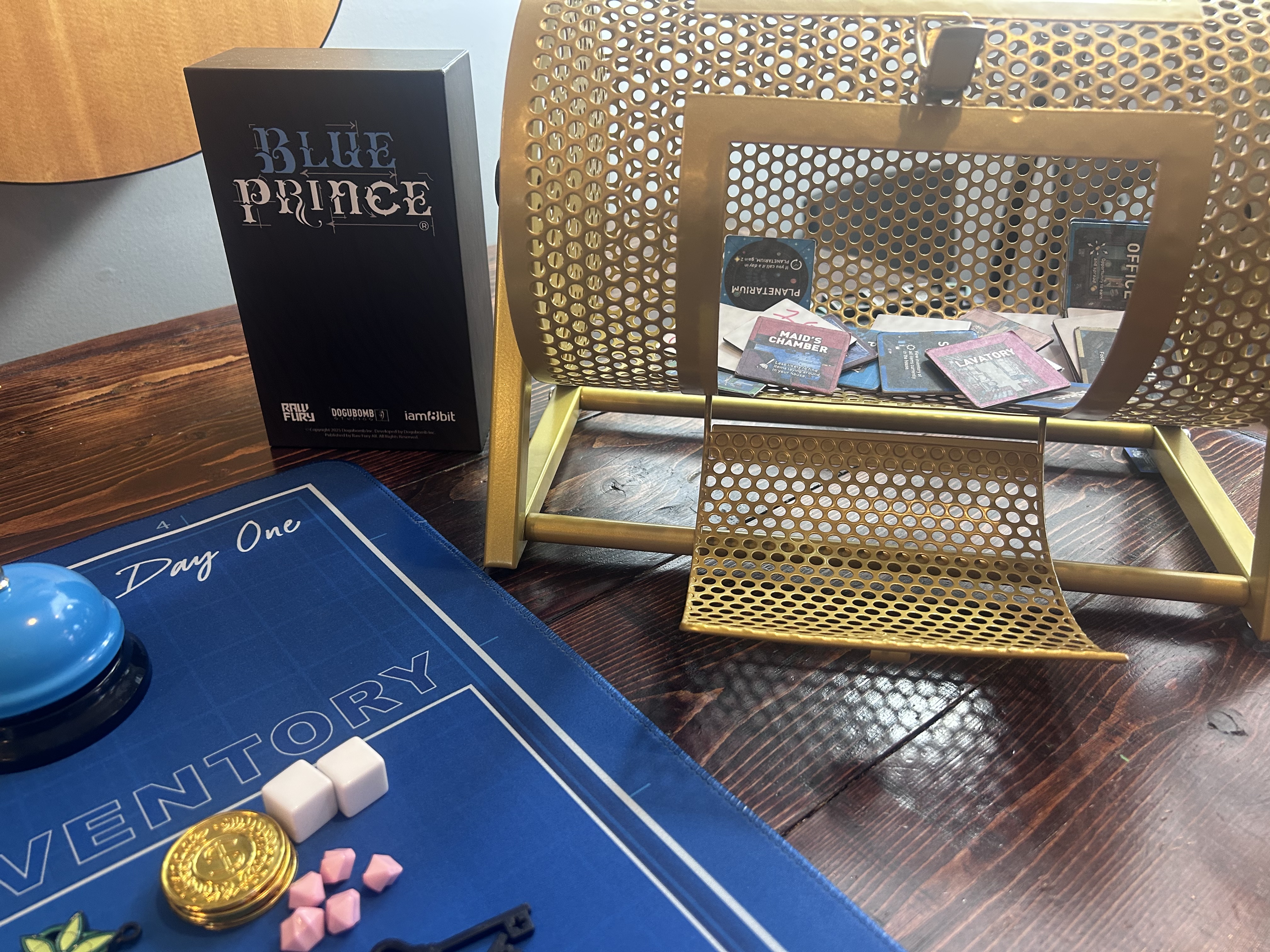 Blue Prince box next to the gold lottery spinner with room tiles visible inside
