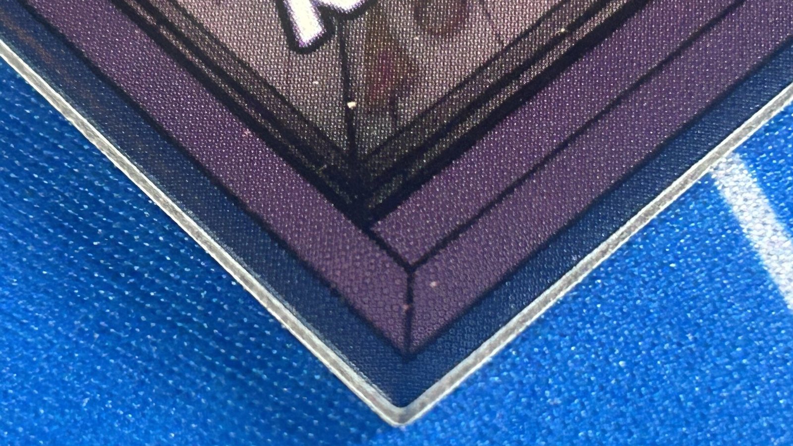 Macro of a purple tile corner showing the clean die-cut edge and the blue bleed rim outside the purple frame