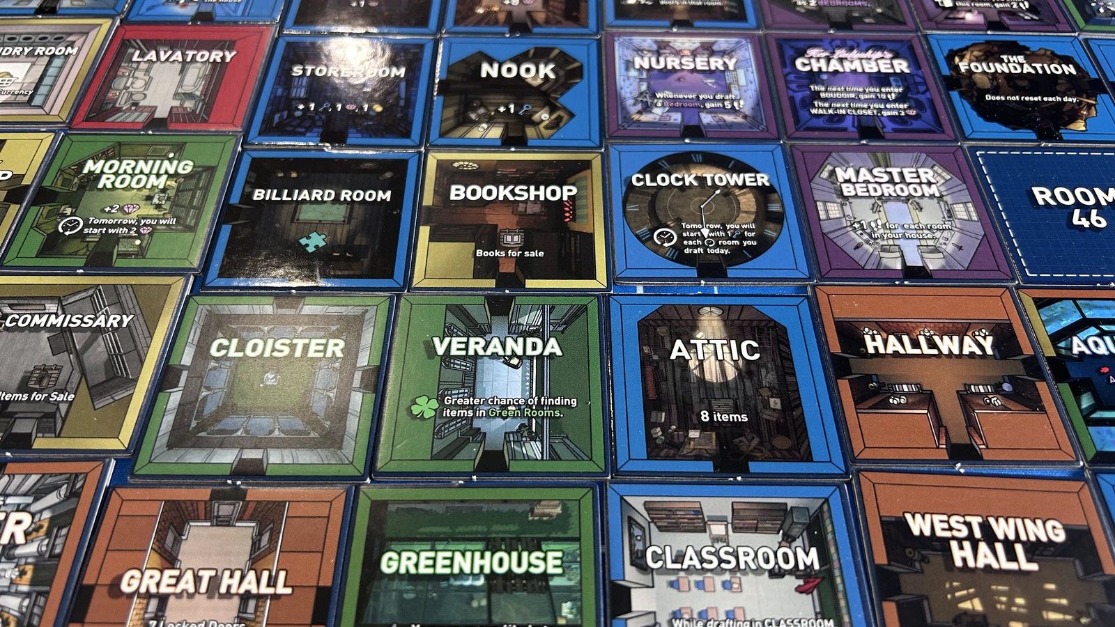 The produced tile set laid out in a grid on the mat: Cloister, Veranda, Attic, Hallway, Greenhouse, Classroom, Clock Tower, Master Bedroom and more