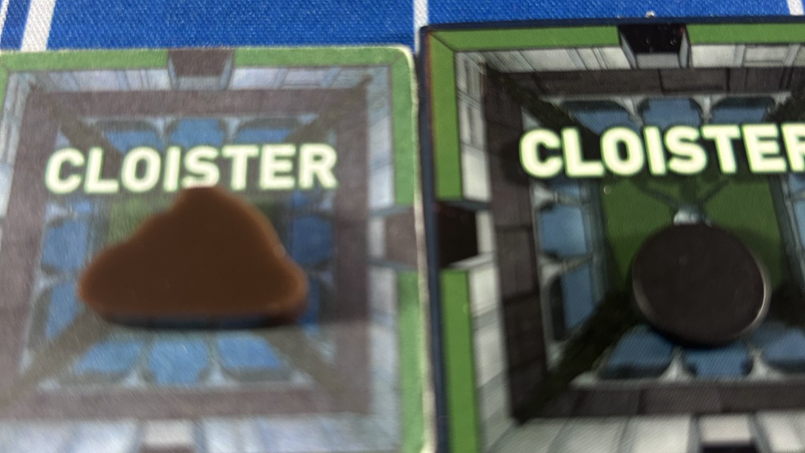 Two Cloister tiles: the old prototype with a sculpted brown dirt pile, the produced tile with a plain black metal disc