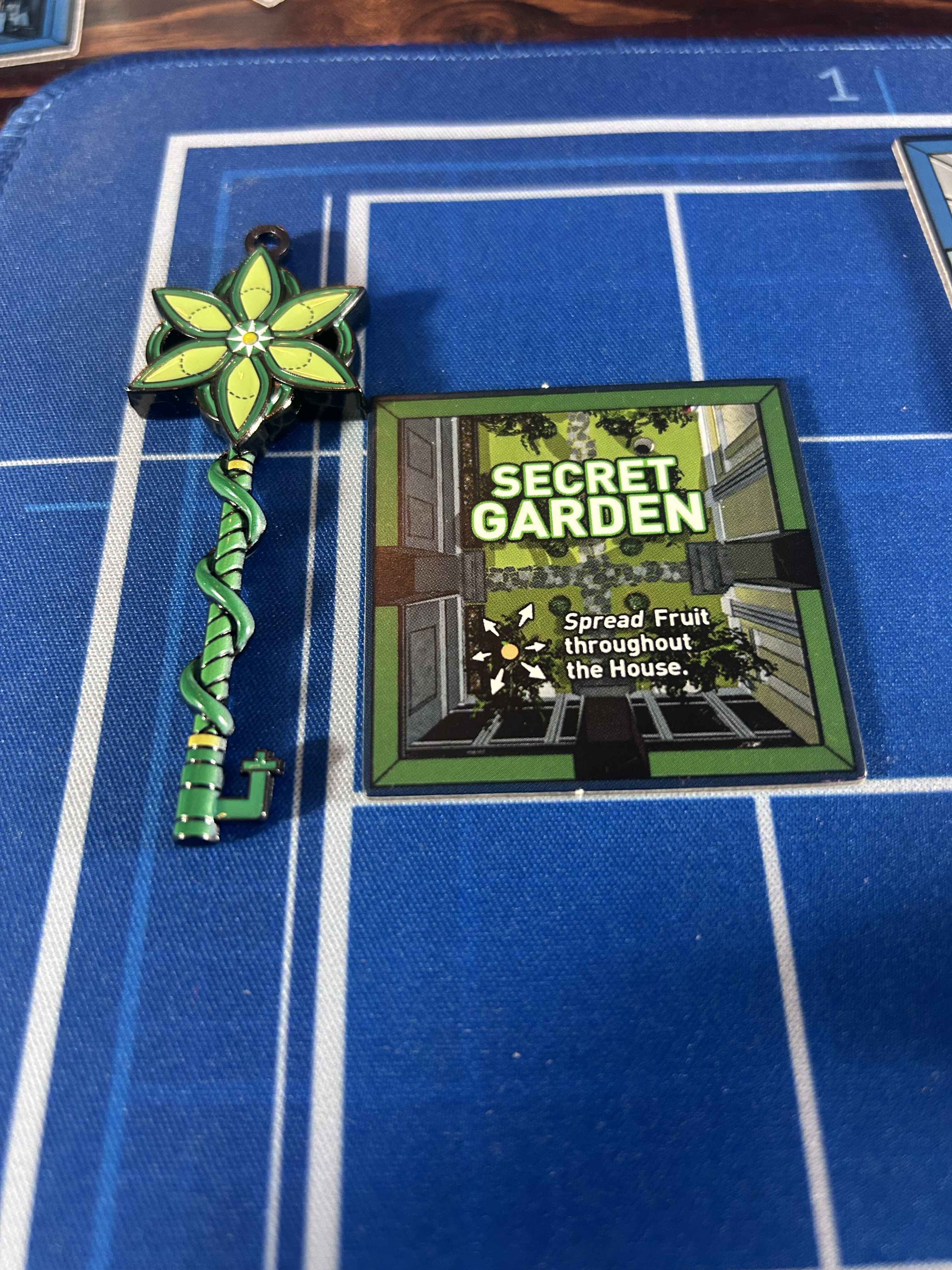 A painted green flower-and-vine key prop beside the Secret Garden tile